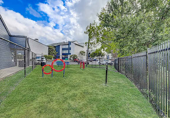 a fenced in dog park with agility courses and agility ropes