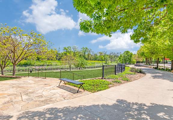 A park with a bench and a fence.