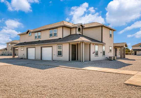 A large house with a gravel driveway in front of it.