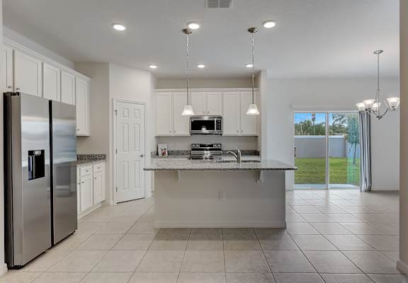 A modern kitchen with a refrigerator, sink, and cabinets.