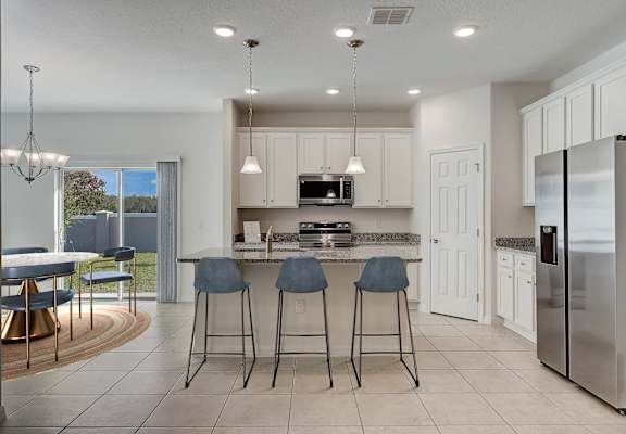 A modern kitchen with a bar area and a refrigerator on the right.