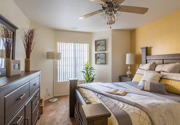 A bedroom with a bed, dresser, and ceiling fan.