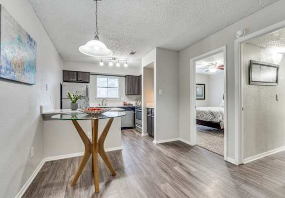 A modern kitchen with a glass table and a wooden X base.