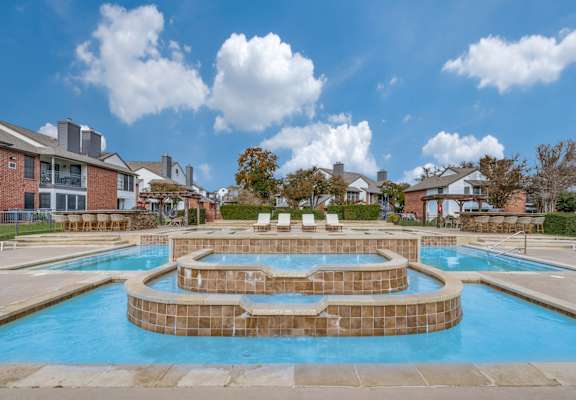 A large outdoor swimming pool with a hot tub in the middle.