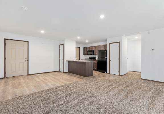 A spacious living room with a kitchen area in the background.
