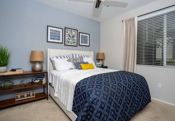 A bedroom with a bed, nightstands, and a plant.