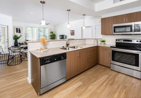a large kitchen with stainless steel appliances and wooden cabinets at Monument, Chandler, AZ 85224