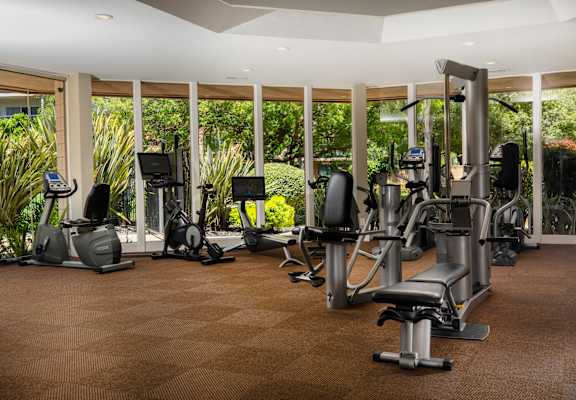 A gym with a variety of equipment including treadmills, stationary bikes, and weight machines.