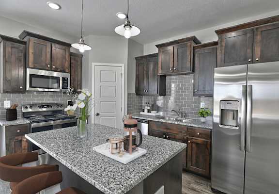 A modern kitchen with a granite countertop and stainless steel appliances.
