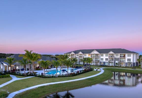a large building with a pool and a lake at dusk