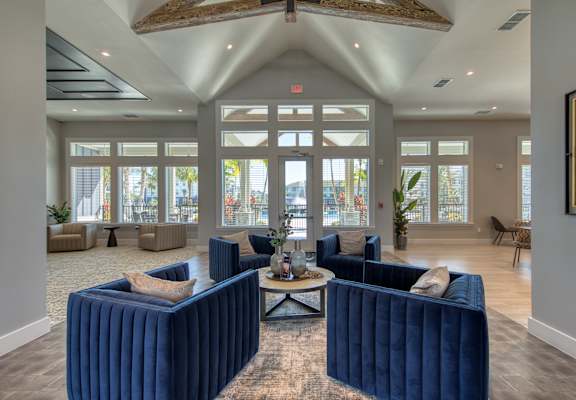a large lobby with blue couches and chairs and windows