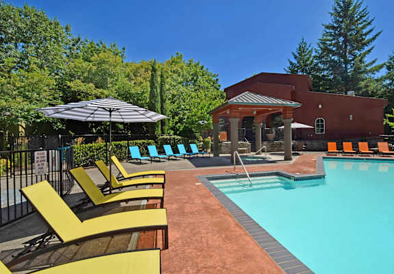 A pool area with a red building and yellow sun loungers.