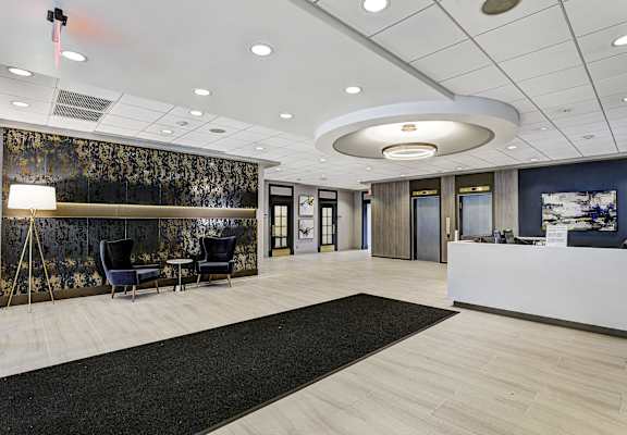 a large lobby with a reception desk and black rugs at The Ivanhoe Apartments, Hackensack, New Jersey