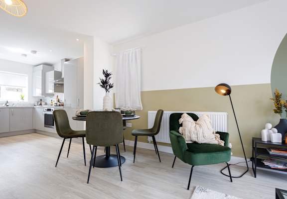 A modern dining room with a green chair and a table with a vase of flowers on it.