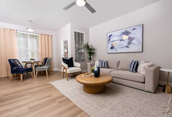 A living room with a couch, chairs, and a painting on the wall.