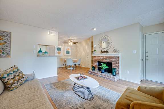 a living room with a fireplace and a couch and a table at Indian Creek Apartments, Carrollton, Texas