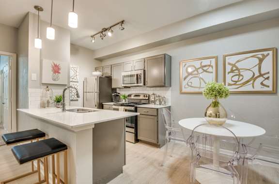 A modern kitchen with a white island and black bar stools.