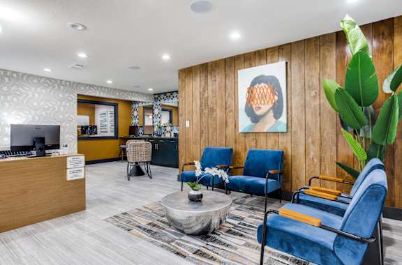 A reception area with blue chairs and a wooden wall.