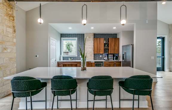 a kitchen with a large white island and green chairs