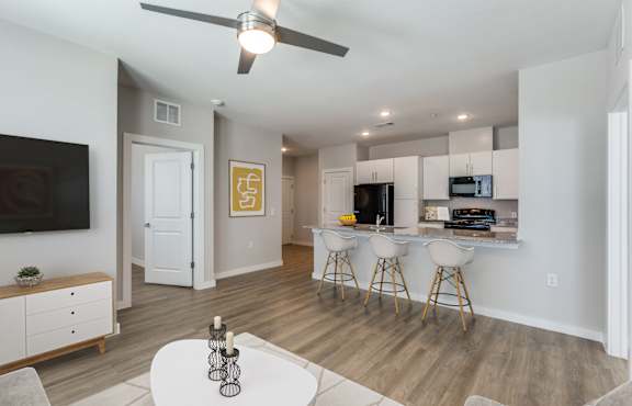 A living room with a white ceiling fan and a white dining table with four chairs.