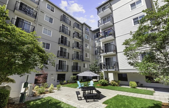 a patio with a table and chairs in front of an apartment building  at King Arthurs Court, Washington