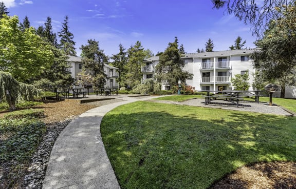 a park with benches and trees in front of an apartment building