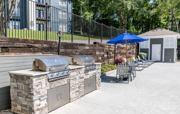 a patio with an outdoor grill and table with chairs at The Atlantic Newtown, Alpharetta, 30022