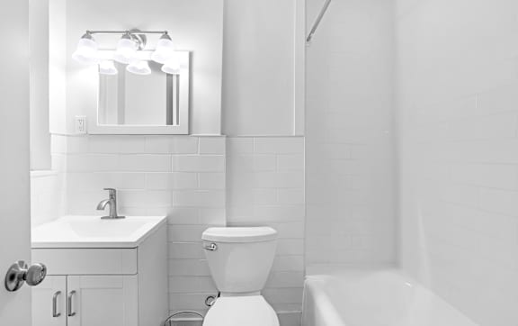 A white bathroom with a toilet, sink, and mirror.at Park Wilshire, Los Angeles California