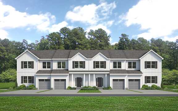 A large white house with a black roof and a grey garage door.