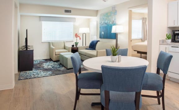 a living room and dining room with blue chairs and a white table at Parks Residential - Richardson, Richardson, 75082