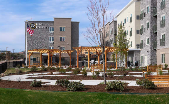 a courtyard with benches and a building with an flag at Parks Residential - Richardson, Richardson, 75082