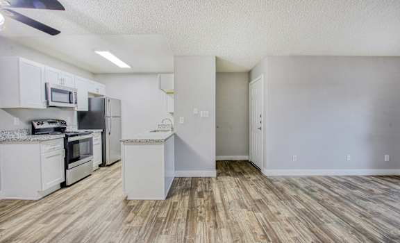 an empty kitchen with white cabinets and stainless steel appliances