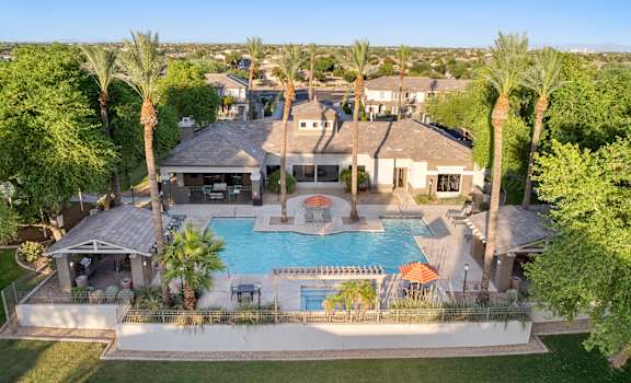 A large house with a pool surrounded by palm trees.