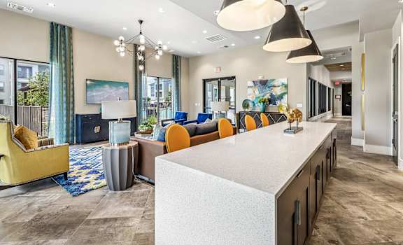 A modern living room with a white counter and orange chairs.