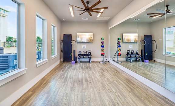 A gym with a mirror, weights, and exercise equipment.