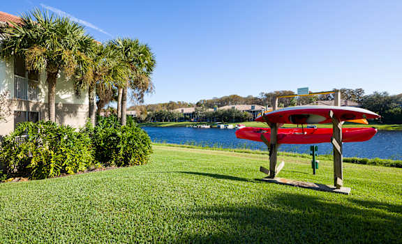 a red plane sits on a picnic table in front of a body of water