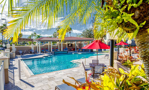 a resort style pool with lounge chairs and umbrellas