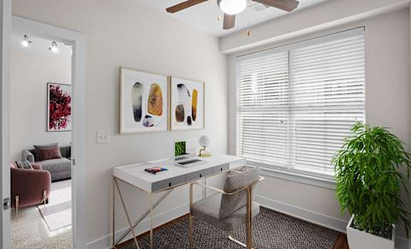 A room with a desk, a chair, a potted plant, and pictures on the wall at West 39th Street Apartments, Kansas City, 64111