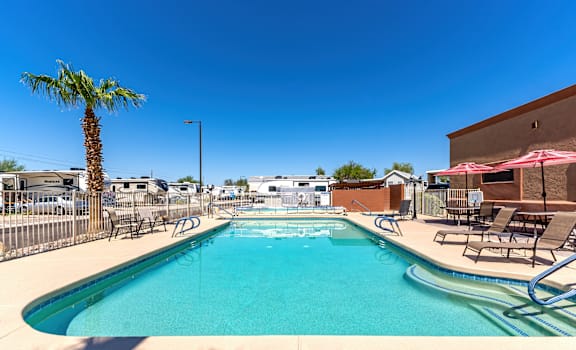 our resort style swimming pool is next to a building and palm tree