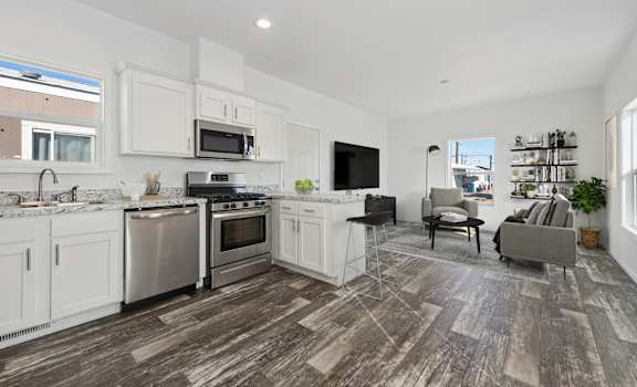 A modern kitchen with white cabinets and a wooden floor.