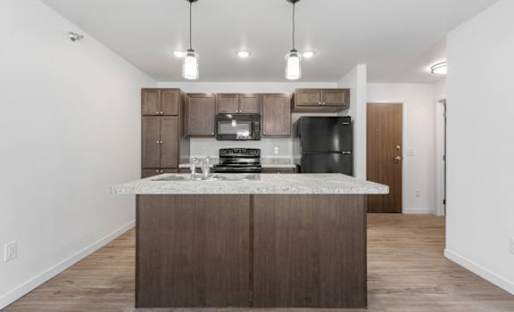 A kitchen with a marble countertop and wooden cabinets.