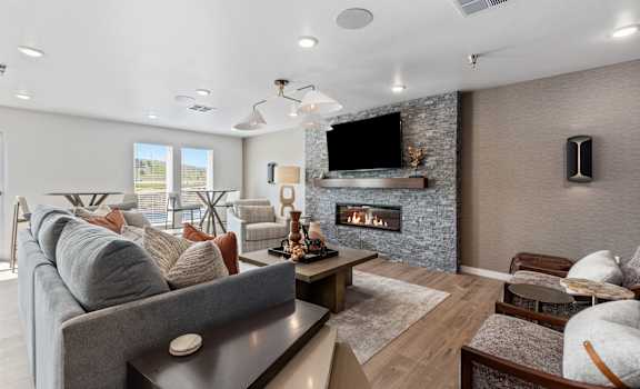 A modern living room with a grey couch, a fireplace, and a flat screen TV mounted on the wall.