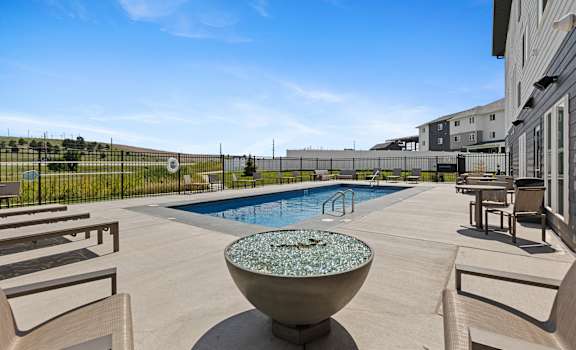 A pool with a fountain in the middle of a patio.