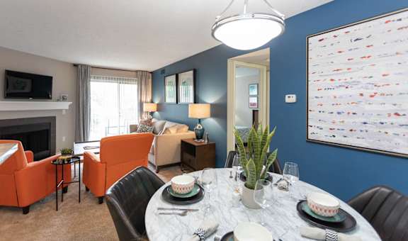 a living room with blue walls and a dining room with a table and chairs at Chinoe Creek Apartments in Lexington KY