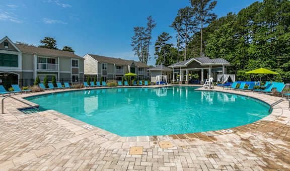 a resort style swimming pool with blue chairs and umbrellas