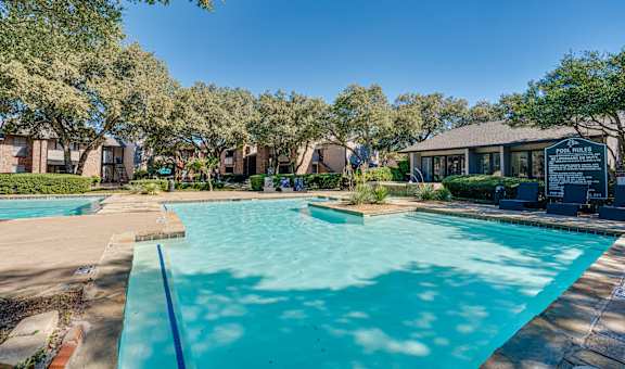 A pool surrounded by trees and a building in the background. at Southern Oaks, Texas