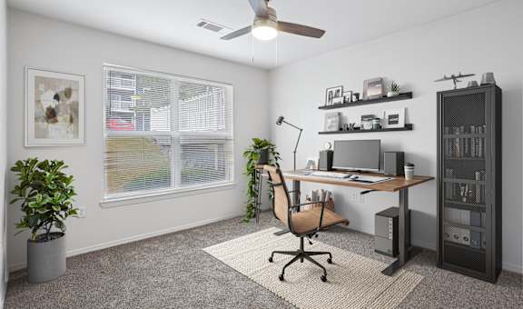A room with a desk, chair, and a ceiling fan.