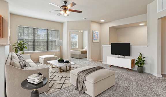 A living room with a ceiling fan and a flat screen TV.