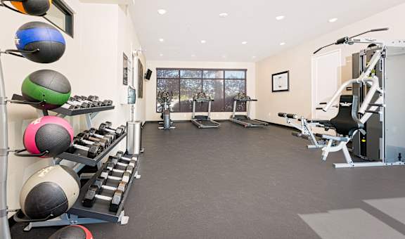 a spacious fitness room with weights and cardio equipment