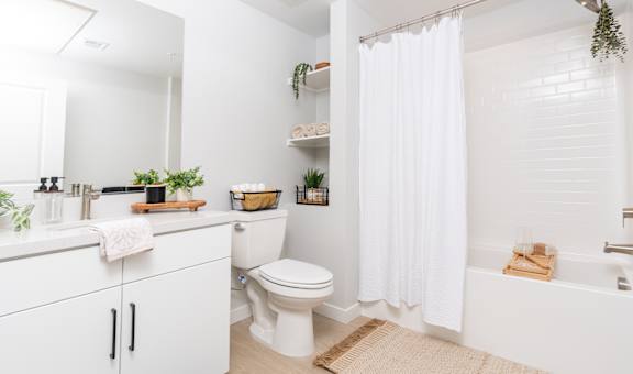 A white bathroom with a toilet, sink, and a shower curtain.